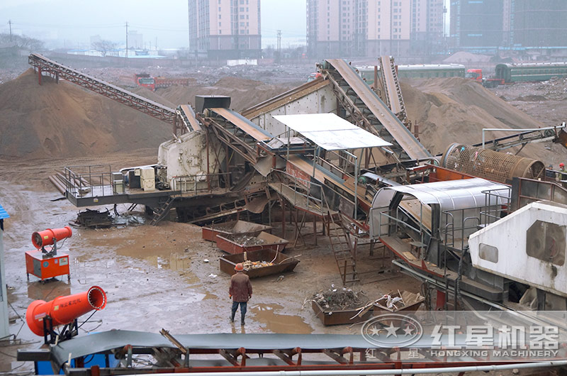 環保破碎站設備正在處理建筑垃圾，配置霧炮機除塵